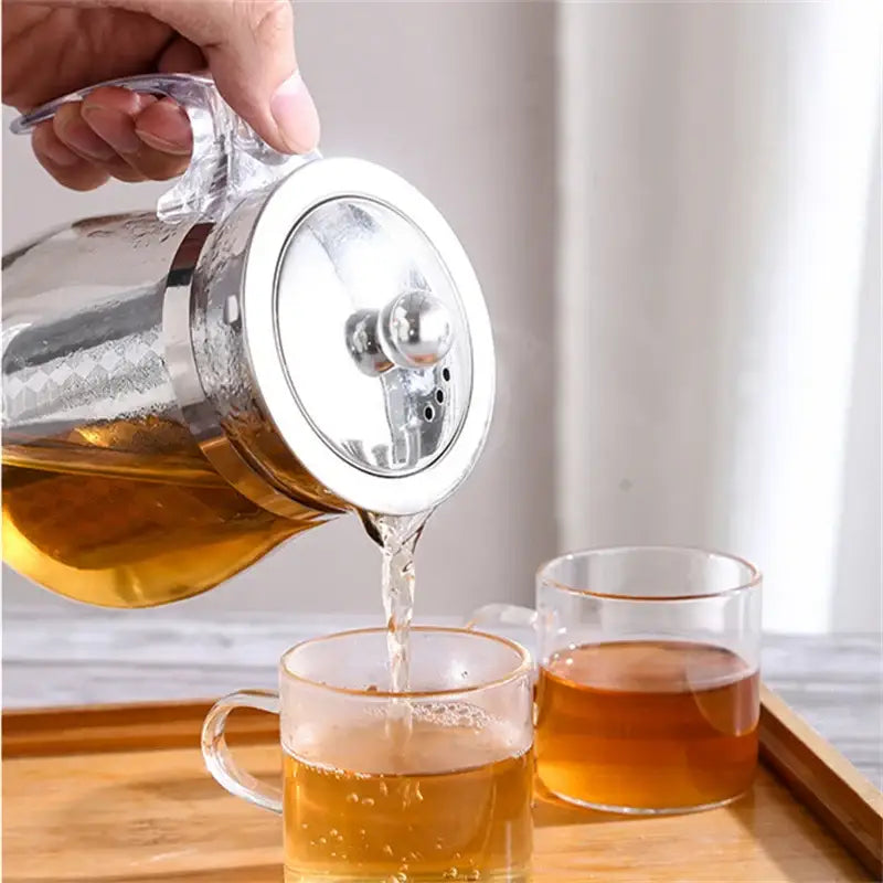 Tea infuser sitting on a wooden table with tea leaves