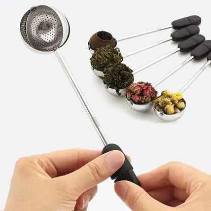Tea infuser ball open on hinge filled with loose leaf tea leaves