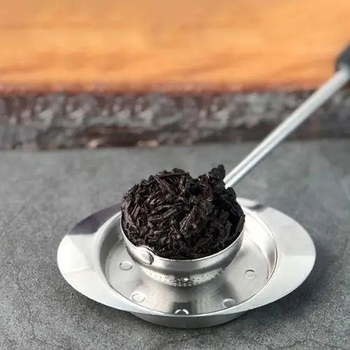 Stainless steel tea infuser ball steeping loose leaf tea in a glass teapot