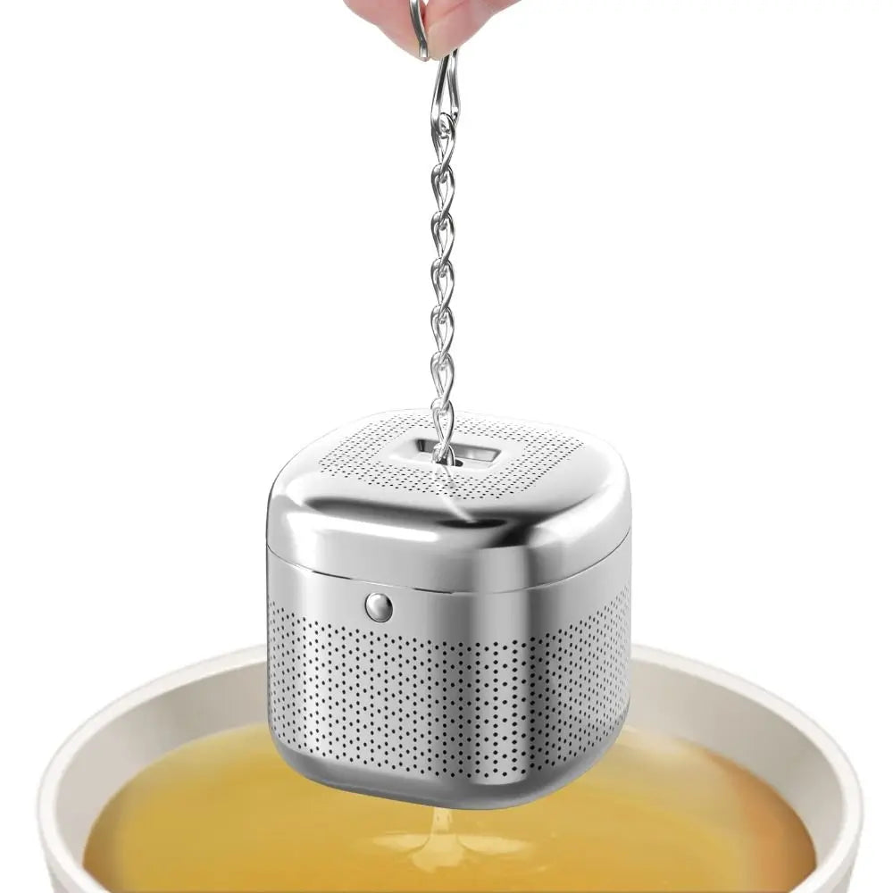 Close-up of stainless steel tea infuser cube with hanging chain