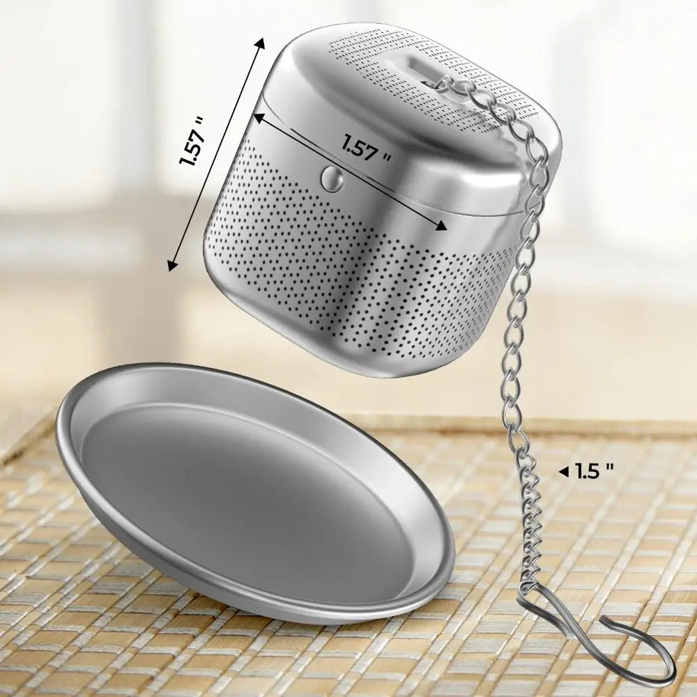 Stainless steel loose leaf infuser cube resting on a ceramic saucer