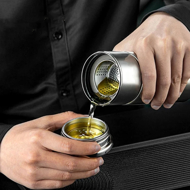 Removable stainless steel infuser basket lifted out of double wall tea thermos
