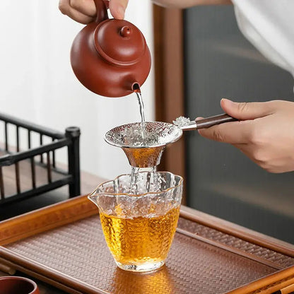 Stainless steel tea strainer with drip tray on wooden table