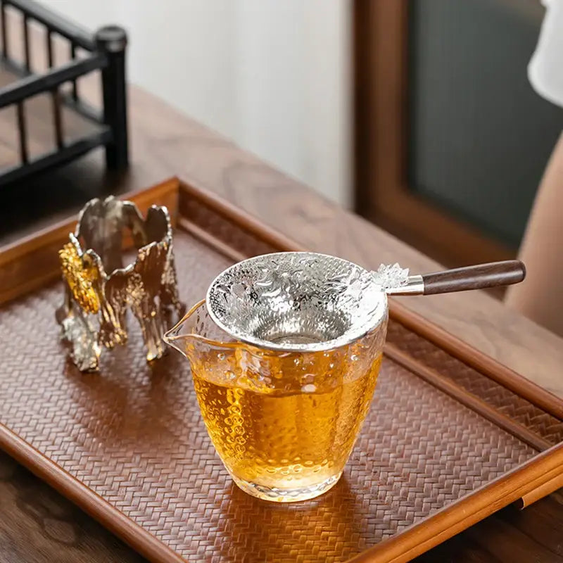 Tea strainer with drip tray next to a teapot