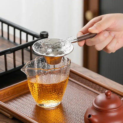 Pouring tea through stainless steel strainer into cup