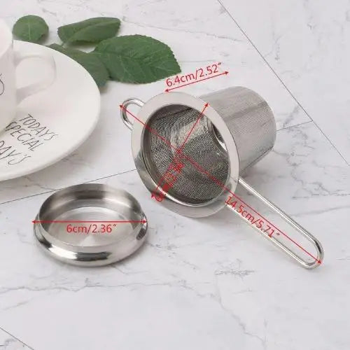 Stainless steel tea strainer next to loose-leaf tea on wooden surface