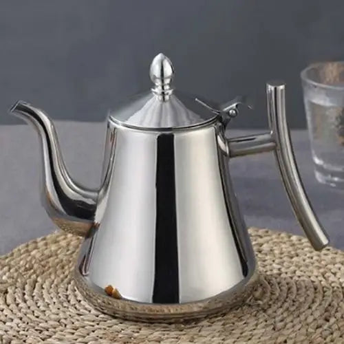 Stainless steel teapot pouring brewed tea into a cup