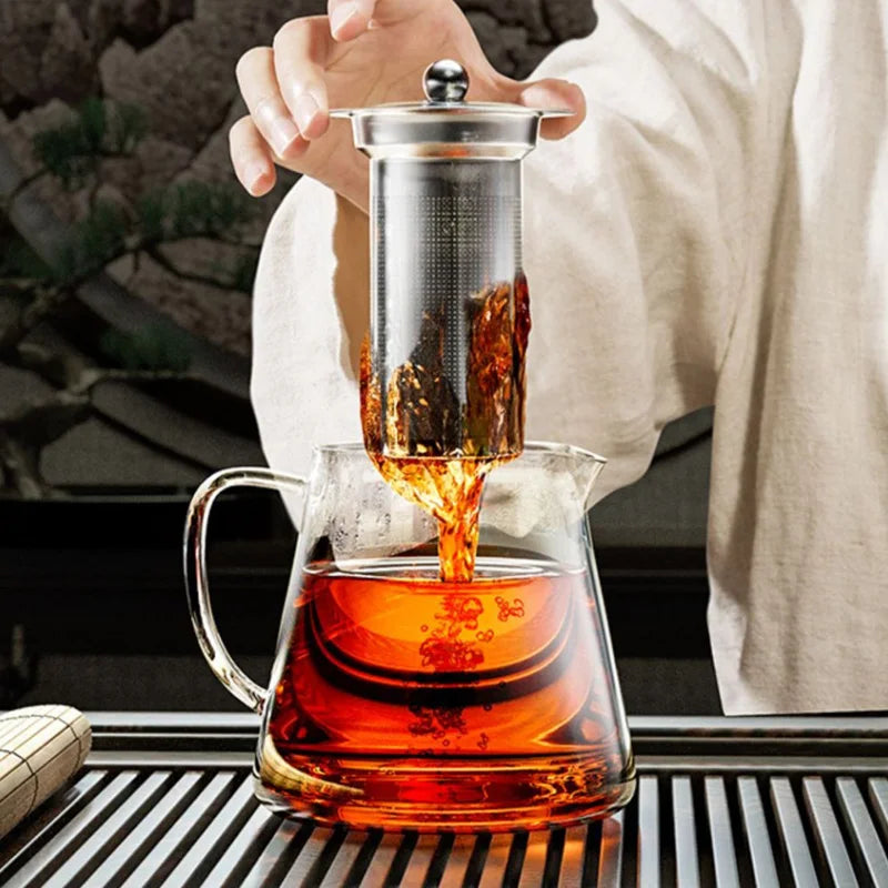 Stainless steel teapot with infuser basket on a wooden kitchen table