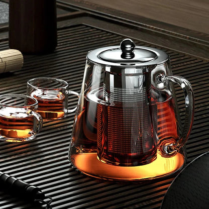 Hot tea pouring from a stainless steel teapot with built-in steel infuser