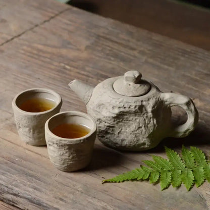 Stone style teapot and cups set arranged on a wooden table