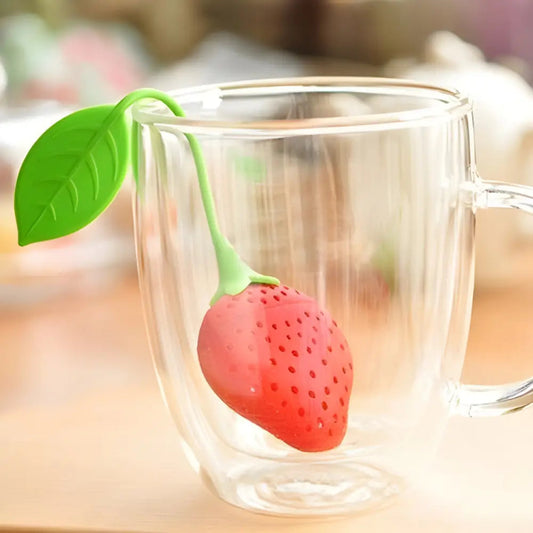 Strawberry silicone tea infuser resting in a ceramic tea cup