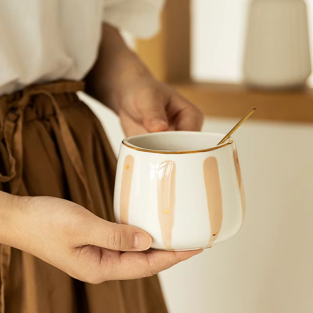 Striped porcelain tea cup beside a ceramic teapot on a wood table
