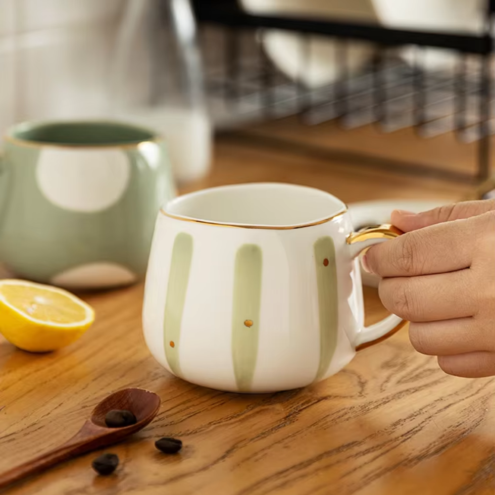 Striped porcelain cup with loose-leaf infuser and teaspoon alongside