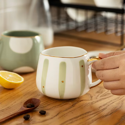 Striped porcelain cup with loose-leaf infuser and teaspoon alongside