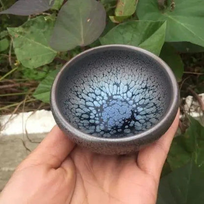 Japanese tenmoku stoneware tea bowl held in two hands, traditional style