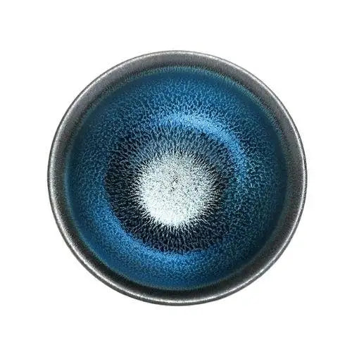 Wide tenmoku matcha bowl with dark iron glaze on wooden table