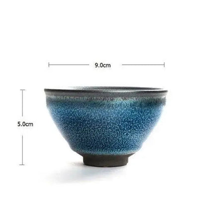 Handmade tenmoku ceramic matcha bowl held in hand showing size reference