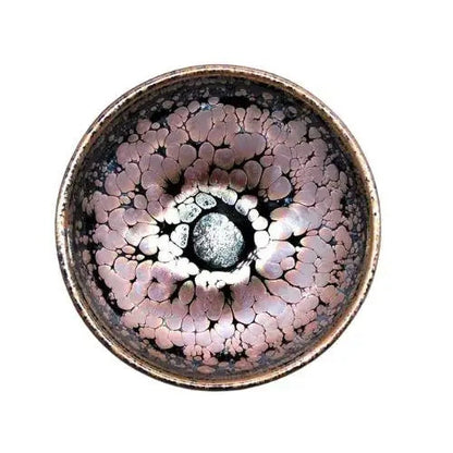 Handcrafted Tenmoku chawan with dark iron glaze on wooden table, side view