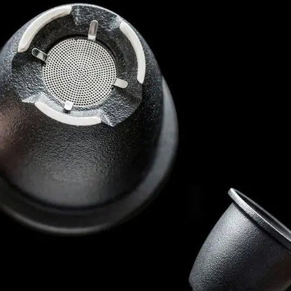Close-up of removable stainless steel infuser basket inside ceramic teapot