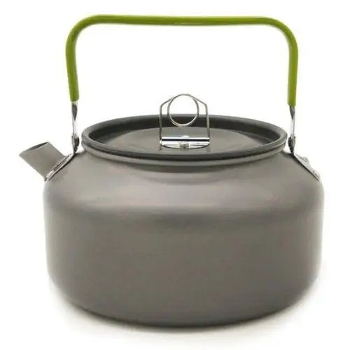Vintage aluminum tea kettle with green handle sitting on gas stove burner