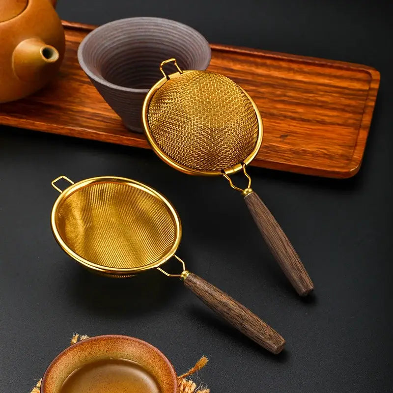 Vintage tea strainer with wooden handle on a saucer