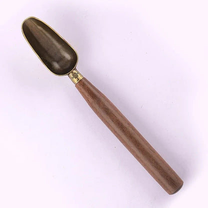 Wooden tea scoop for loose leaf resting on a rustic wood tea tray