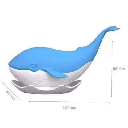 Whale silicone loose leaf infuser resting on saucer beside brewed cup of tea