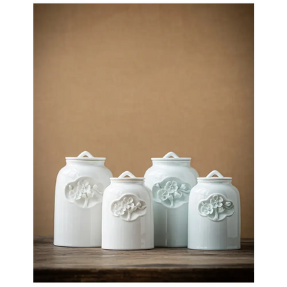 White ceramic tea canister with tea leaves scattered around