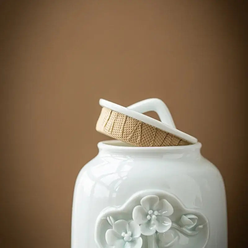 White ceramic tea canister open lid showing loose leaf tea inside