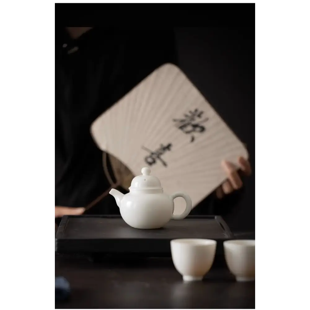 White ceramic teapot with tea leaves