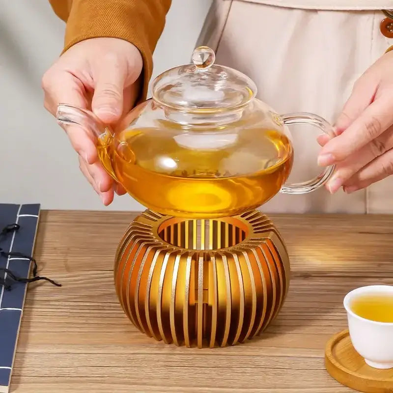 Gold-finish teapot warmer with wood base styled on a tabletop