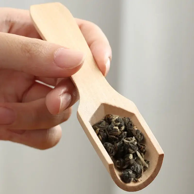 Wooden tea spoon next to a teapot and cup