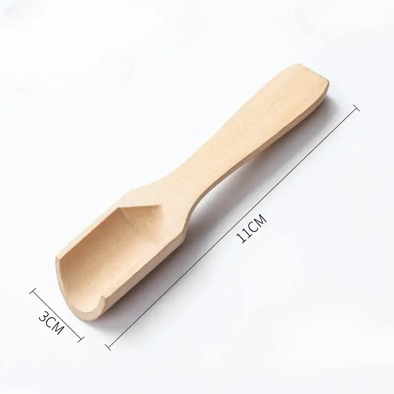 Wooden tea spoon on a kitchen counter with tea accessories