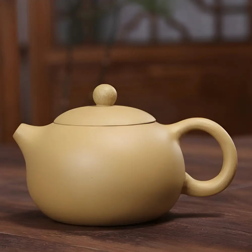Yixing teapot pouring loose leaf tea into small cup